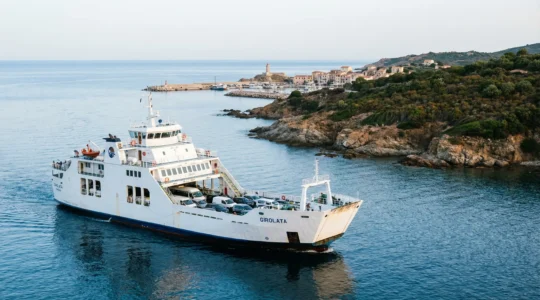 Ferry avec véhicules sur le pont approchant un port corse